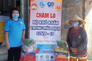 第十一郡第二坊婦女會主席林玉明（左）將民生必需品交給貧困者。