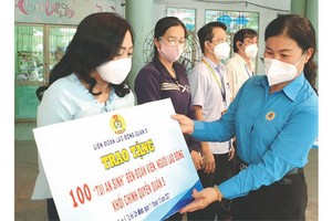 第五郡勞動聯團主席黎氏碧幸(右)向各工會代表派發禮物以轉交給貧困勞動者。