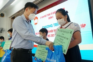 第五郡祖國陣線委員會主席黎晉才向清貧優秀生頒發助學金。（圖源：三源） 