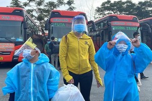 兩名身穿防護服的小孩在母親的陪同下準備上車返鄉。（圖源：文明）