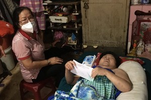 躺在長椅上的李金英伸手接過志願員送來的輔助金。