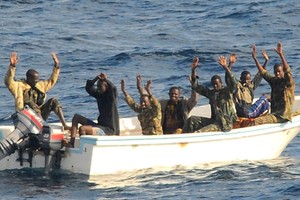 海盜嫌疑份子舉手投降等待反海盜行動人員登上他們小船。（圖：聯合國）