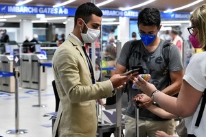 意大利米蘭，工作人員在機場檢查乘客的綠色通行證。（圖：路透社）