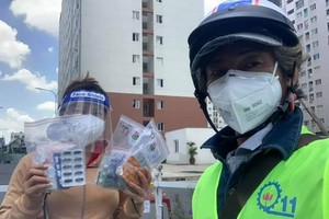 華人攝影家柯成智達(右)派發藥品給新冠患者。