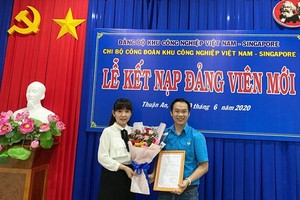 越南-新加坡工業區工會黨支部書記鄧氏金芝向新黨員頒授接納入黨《決定》。