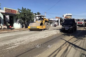 施工單位在擴寬改建途徑寧順省寧山縣仁山鄉公路路面。（圖：越通社）