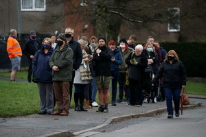 人們在英國巴克斯頓排隊等待接種新冠疫苗加強針。（圖：路透社）