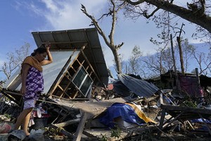 當地時間2021年12月18日，菲律賓宿務，居民在被颱風「雷伊」毀壞的家園前。（圖：互聯網）