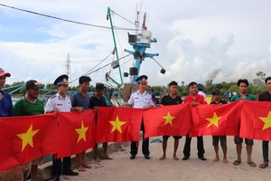 第四區海警司令部代表向堅江省安明縣漁民贈送國旗。（圖：V. Tôn）