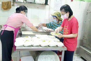 阮翠香（左）和慈善組成員將飯菜舀入盒子裡。