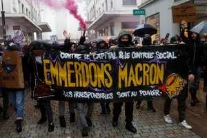 法國南特市民眾上周六帶著寫有斥責總統馬克龍的橫額，抗議政府推行「疫苗通行證」和收緊未接種新冠疫苗人士的出行限制。（圖：路透社）