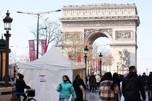 人們走過法國巴黎凱旋門附近的一處新冠病毒檢測點。（圖：新華社）
