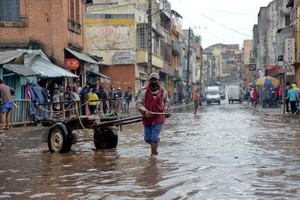 當地時間2月6日，在馬達加斯加首都塔那那利佛，一名男子蹚水走過淹沒的道路。馬達加斯加內政部7日說，強熱帶氣旋“巴齊雷”日前襲擊馬達加斯加，造成至少20人死亡，近7萬人被迫轉移。（圖：新華社）