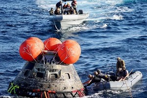 工作人員把降落後的獵戶座太空船固定。（圖：AP）