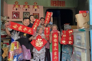梁朝铭（后排右一）与众友向孤寡老人赠送挥春与春联。
