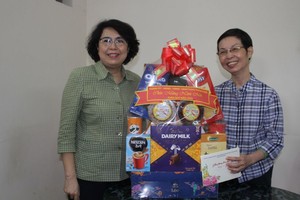 市委常务处委员、第一郡郡委书记苏氏碧珠（左）向华人退休干部姚妙玲赠送贺年礼物。