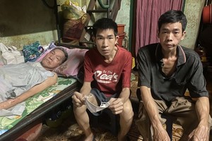 （左起）卧床的朱锦明与两个儿子朱镇鸿和朱镇荣。