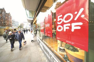 人们走过英国曼彻斯特街上的促销广告。（图：新华社）