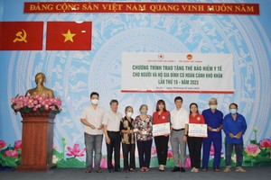 第五郡郡人委会副主席阮武春奇（左二）与穗城会馆理事罗满堂（左六）向贫困者赠送医保卡。