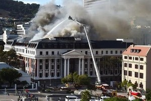 图为 1月3日，消防员在南非立法首都开普敦对发生复燃的议会建筑进行灭火作业。（图：新华社）
