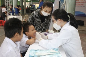 白衣志愿者为少儿做口腔检查。