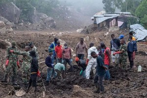 热带气旋“弗雷迪”给马拉维带来倾盆大雨，南部布兰太尔山区17日发生泥石流，国防军和民众在一片泥泞中合力寻找遇难者遗体。（图：AFP）