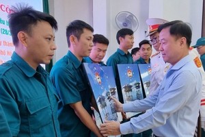 郡越南祖国阵线委员会主席黎晋才向各模范自卫民兵队赠送礼物。