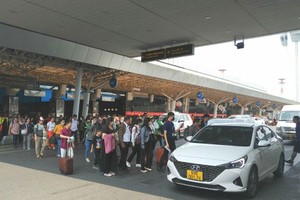 人流横跨新山一机场的汽车道。