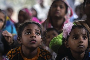 在印度古瓦哈提 (Guwahati) 的一个棚户区，女孩和她们的母亲正在一个关于童婚问题的宣传营中听取一名非政府组织工作人员的讲话。（图：AP）