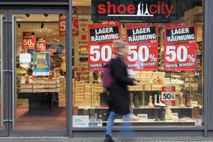 一名女子经过德国柏林的一家打折店铺。（图：新华社）