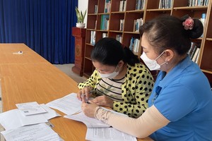 古芝县越南Samho有限责任公司工会干部指引劳工（左）按第6696号《决定》办理申请辅助卷宗。