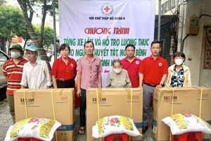 红十字会主席黎氏宝庄（左三）、副主席张世强（右二）与热心人士陈弟（左四）等向残疾人士赠送轮椅与大米。