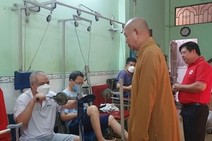 郡红十字会主席阮国明及辅助会会长释慧功法师正慰问贫困病人的身体状况。