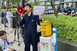 2023年6月7日，来自环保组织绿色韩国联合会的一名活动人士在日本驻首尔大使馆前举行了抗议活动，当时他站在一个净水器旁边，该净水器连接在一个模拟的福岛污染废水桶上。（图：互联网）