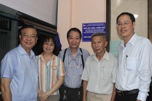 市越南祖国阵线委员会常务副主席阮成忠（右一）和庆云南院住持周华邦（中）与地方领导向裴文春一户移交温情屋。