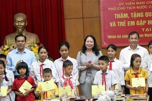 国家副主席武氏映春（后中）向家境清贫少儿赠送礼物。（图：越通社）