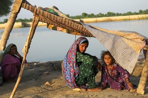 在巴基斯坦信德省，一家人在逃离遭受洪水袭击的家园后，在路边栖身。（图：联合国）