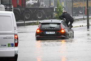 2023年8月7日，瑞典马尔默（Malmo）郊外，洪水侵袭高速公路，一名乘客试图爬出汽车逃生。（图：AFP）
