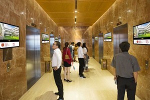 人们在等候电梯时观看楼宇电梯视频广告。