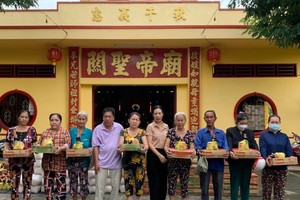 安乐A坊越南祖国阵线委员会主席阮氏青翠（右五）和决胜村关帝庙理事长杨振明（左四）和向贫困者派发盂兰节礼物。