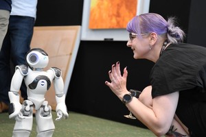 2023年7月7日，在瑞士日内瓦“人工智能造福人类全球峰会”上，一名参会者与机器人互动。（图：新华社）