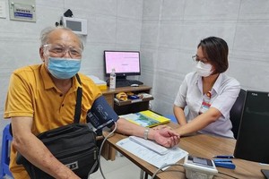 本月内为高龄人免费诊治病。图为医护人员在为一位高龄者测量血压。（图：海燕）