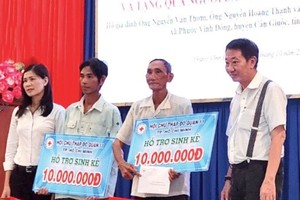 茶山庆云南院住持周华邦（右一）向贫困渔民赠送生计。