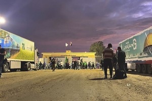 多辆载着救援物资的货车停泊在拉法口岸。（图：AP）