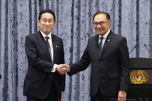 日本首相岸田文雄（左）与马来西亚总理安瓦尔结束联合记者会后握手。（图：共同社）