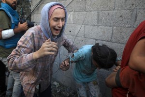 6日，人们从加沙地带中部地区一处被炸难民营逃离。（图：新华社）