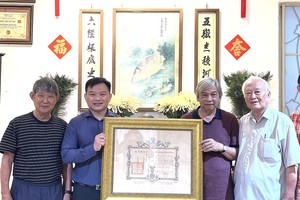 陈马尚收藏家（左三）向笔者赠送保大王1942年御赐的证书。左一为李克柔画家，右一为邬有发书法家。