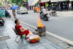 一名老妇在桃街旁焚烧冥纸。（图：越通社）