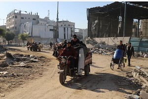 人们经过加沙城受损的建筑。（图：新华社）