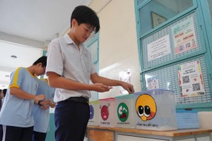 第一郡梁世荣高中学校的学生将卵石放入情绪识别箱中。